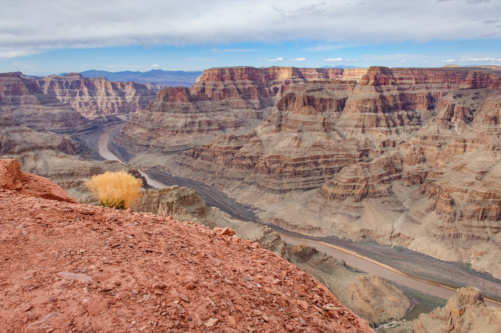The Colorado River seen from above, winding between layered red canyon walls.