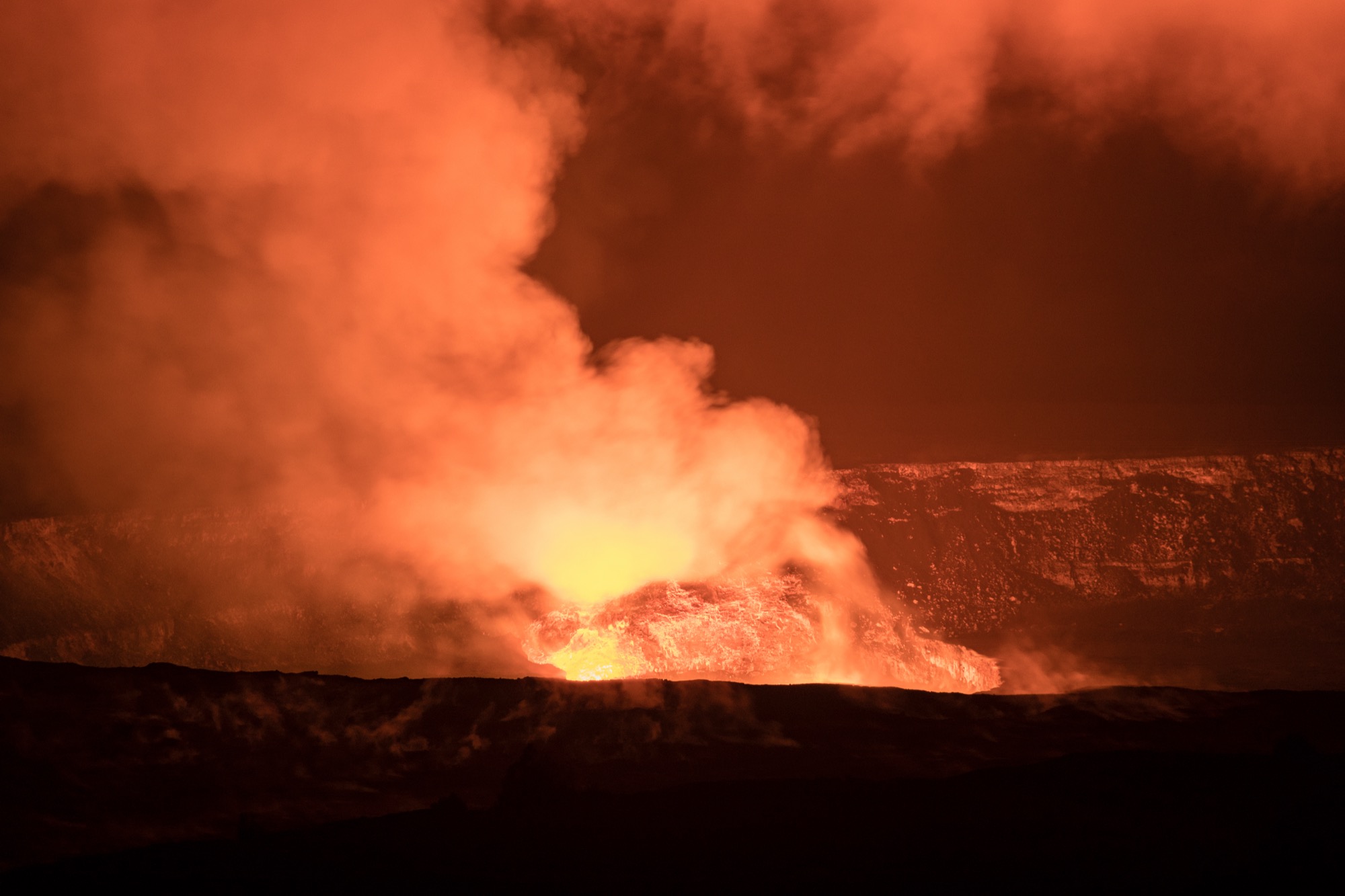 Steam and smoke rising from a volcanic crater, glowing red from lava beneath.