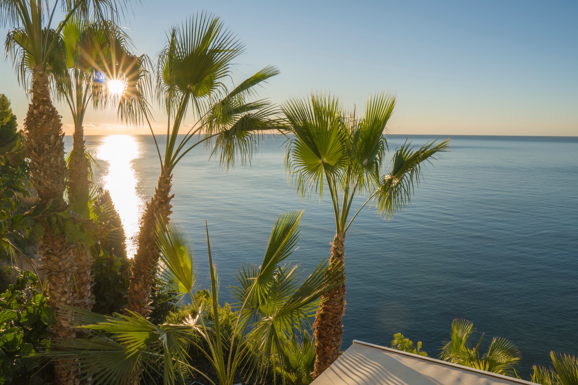 The sun rising over a calm Mediterranean Sea, seen from the shore at Altea.