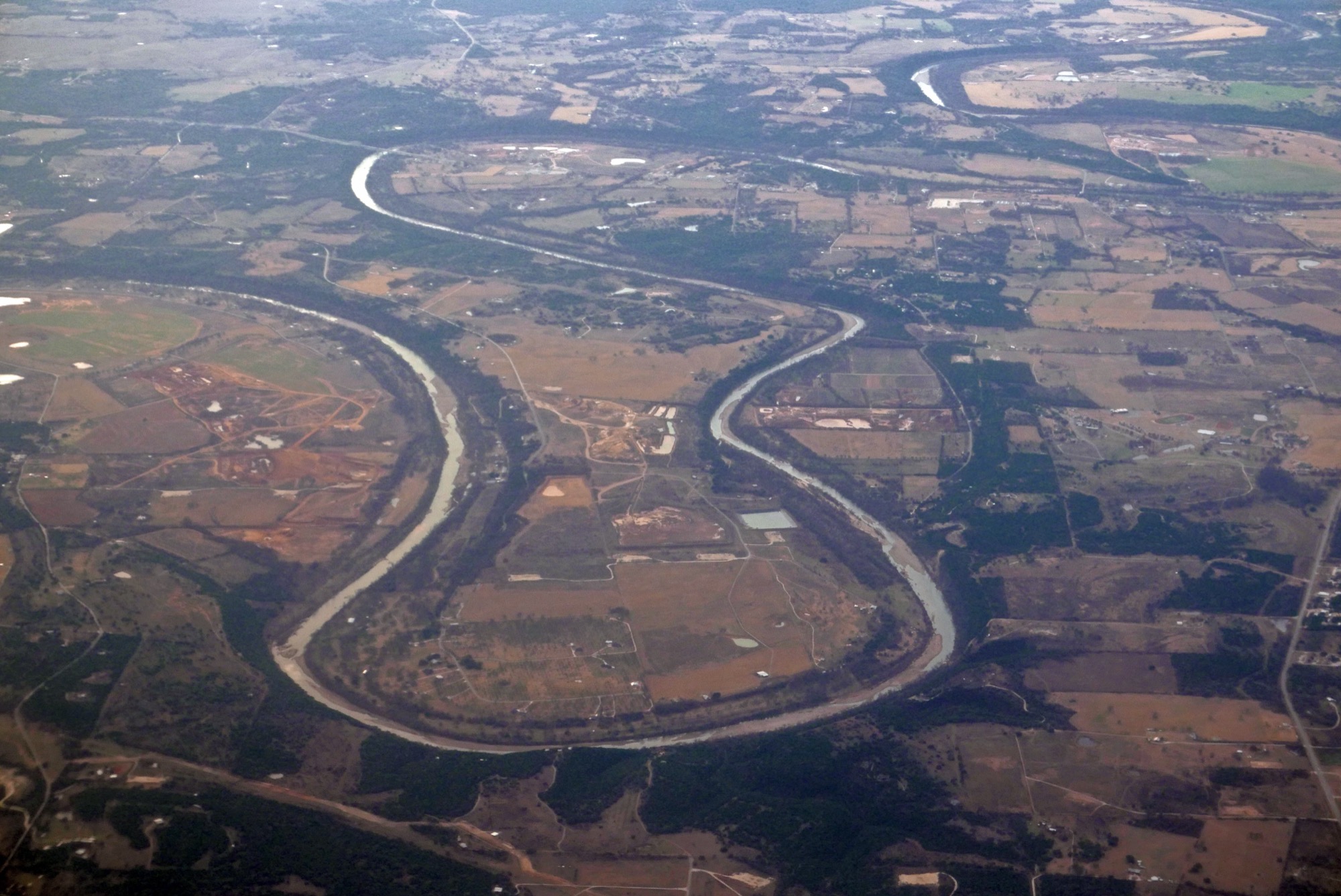 An aerial view of a river meandering across a green plain.