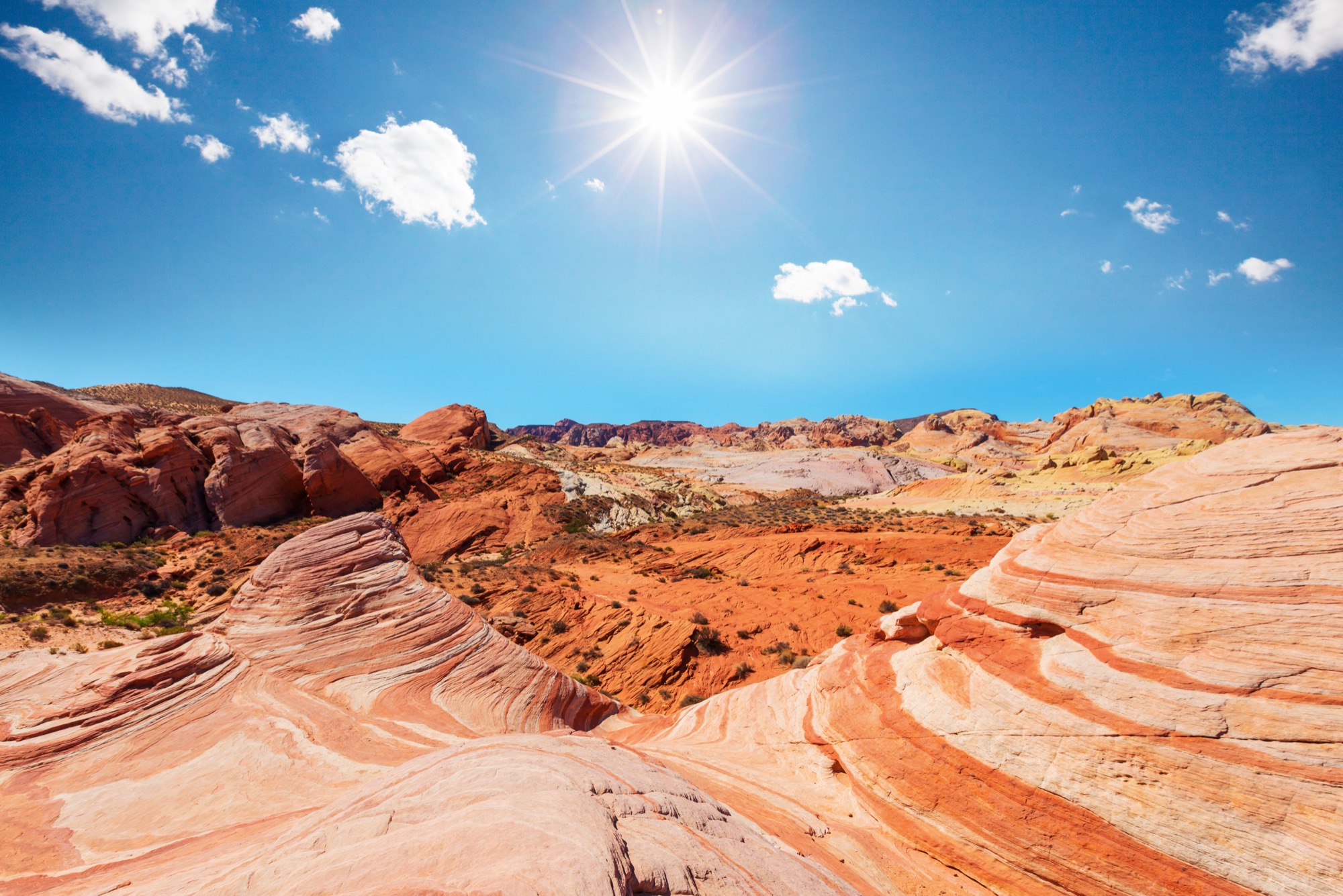 Swirling red and orange sandstone in Valley of Fire State Park, Nevada, under a blue sky.